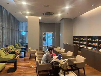 two people sitting in a waiting room with their laptops at Infinity Skypool Retreat hostel in Kuala Lumpur