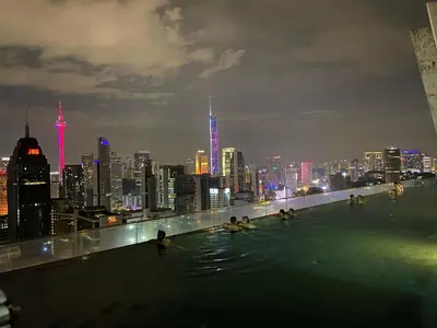 a group of people swimming in the infinity pool of a building with a city at Infinity Skypool Retreat hostel in Kuala Lumpur