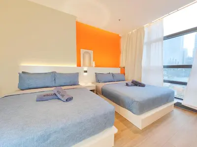 two beds in a bedroom with an orange wall at Weekly Monthly Stay - Bangsar Trade Centre Aspire in Kuala Lumpur