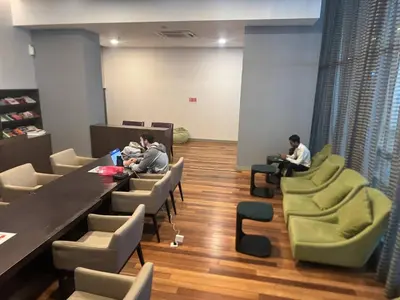 two people sitting at tables and chairs in a room at Elevated Horizons Hostel & Infinity Suites Skypool in Kuala Lumpur