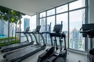 a gym with cardio machines in front of a large window at Le Luxe de KL 2BR with Bath Tub 10 min to KLCC in Kuala Lumpur