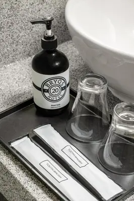 a bottle of soap and two glasses on a counter at BRYQS Hotel KL Sentral in Kuala Lumpur