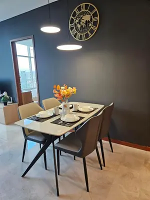 a dining room table with chairs and a clock on the wall at Sky Suites KLCC Level 58 in Kuala Lumpur