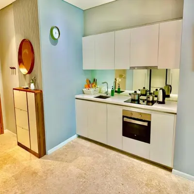 a kitchen with white cabinets and a blue wall at Sky suites klcc by Elham in Kuala Lumpur