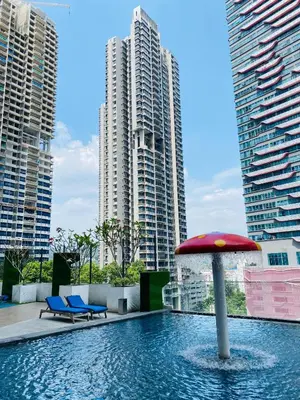 a pool with a red umbrella and some buildings at Reizz by Aayu Residences - 10mins to KLCC, 2 mins to Gleneagles Hospital in Kuala Lumpur