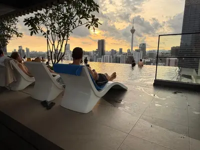 a group of people sitting in chairs next to a swimming pool at Residensi Akson Bukit Bintang Axon nearby Pavilion TRX in Kuala Lumpur
