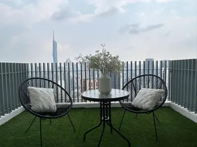 a table and two chairs with a vase on a balcony at The Luxe by Infinitum Suites in Kuala Lumpur