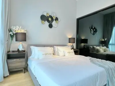 a bedroom with a large white bed with a clock on the wall at The Luxe by Infinitum Suites in Kuala Lumpur
