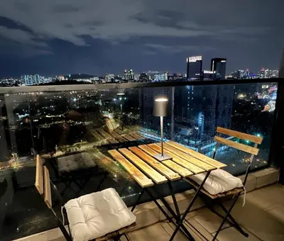 a table and chairs on a balcony with a city skyline at The Establishment Bangsar #23a by Ouki in Kuala Lumpur