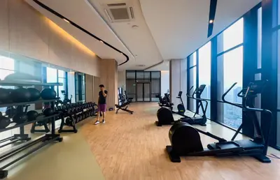 a woman standing in a gym with cardio equipment at Axon Residences KLCC - Premium Suites in Kuala Lumpur
