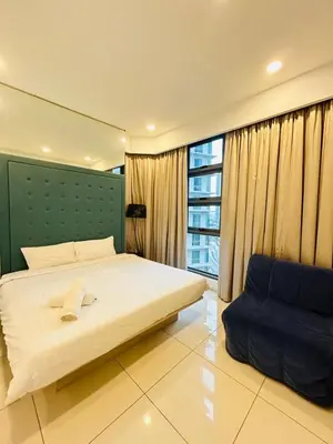 a bedroom with a bed and a blue chair at Robertson Suites At Bukit Bintang Kuala Lumpur in Kuala Lumpur