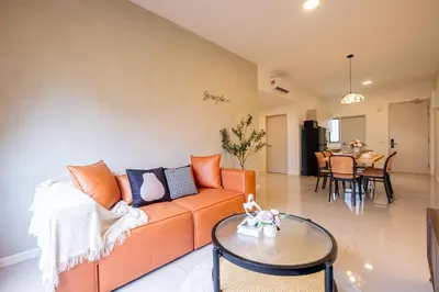 a living room with an orange couch and a table at Kids Friendly Homestay at Riana Dutamas in Kuala Lumpur