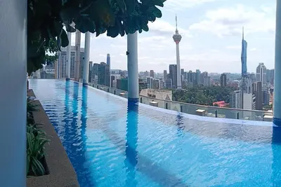 a swimming pool on top of a building with a city skyline at Colony by infinitum KLCC in Kuala Lumpur