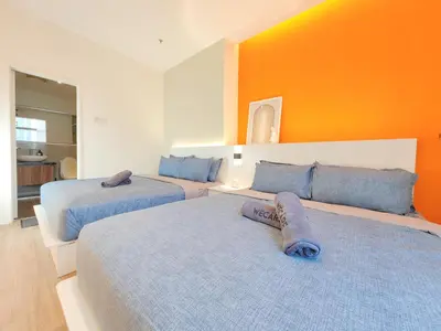 two beds in a room with an orange wall at The Aspire - Bangsar Trade Centre in Kuala Lumpur