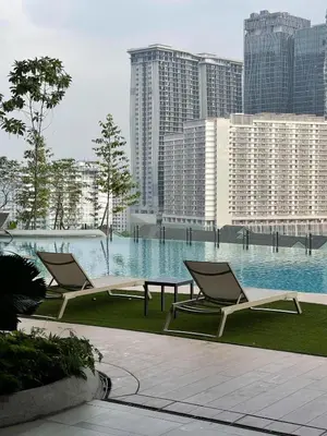 two lounge chairs and a table in front of a pool at Cozy Urban Retreat in the Heart of the Bangsar in Kuala Lumpur
