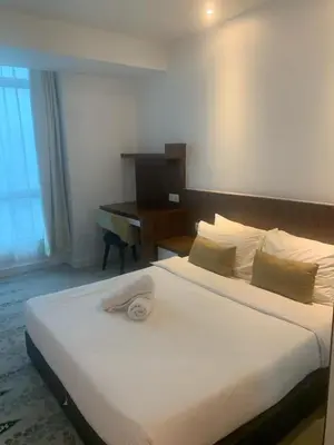 a bedroom with a large white bed with a desk at RaarFAM Homestay in Kuala Lumpur