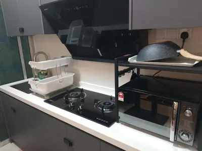 a kitchen counter with a stove and a microwave at Anaqi Homestay by Razak City Sg Besi in Kuala Lumpur