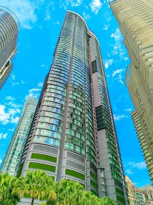a tall building with palm trees in front of a blue sky at Sky Suites KLCC Kuala Lumpur LB in Kuala Lumpur