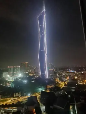 a tall tower lit up at night in a city at The Roberstson family suite with city views in Kuala Lumpur