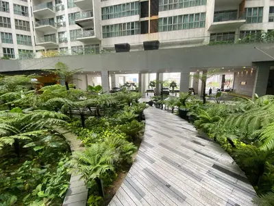 a walkway in a building with plants and tables at CloudNest Infinity Sky pool Hostel in Kuala Lumpur