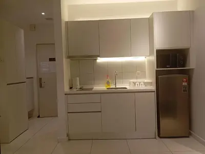 a kitchen with white cabinets and a stainless steel refrigerator at chamber suites by bintang in Kuala Lumpur