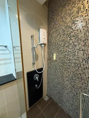 a shower in a bathroom with a tiled wall at Swiss Garden Residences by Roomy in Kuala Lumpur