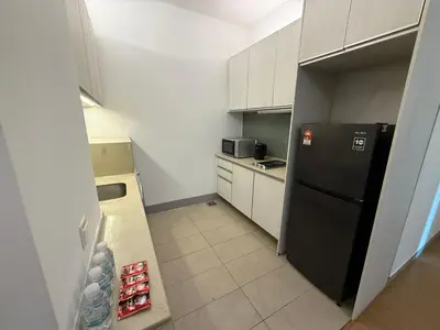 a kitchen with a black refrigerator and white cabinets at Swiss Garden Residences by Roomy in Kuala Lumpur