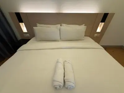a white bed with two towels on it at Swiss Garden Residences by Roomy in Kuala Lumpur