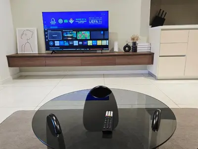 a remote control sitting on a glass table in front of a tv at Quill Residence KL Suites in Kuala Lumpur
