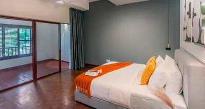a bedroom with a bed with orange and white pillows at Embassy Villa by Cobnb at Ampang Hilir in Kuala Lumpur