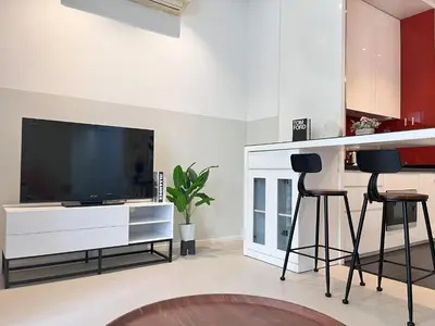 a living room with a large television and two bar stools at Arcoris SOHO by Cj in Kuala Lumpur