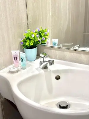 a white bathroom sink with a mirror and flowers at Central City Hotel at Chinatown in Kuala Lumpur