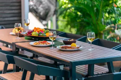 a wooden table with plates of food and glasses of wine at Flame of the Forest Retreat 38Pax 8R7B Pool Villa Kuala Lumpur in Kuala Lumpur