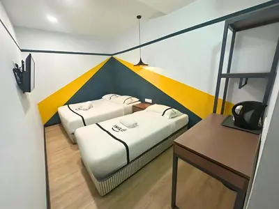 two beds in a small room with a desk at Seeds Hotel Bukit Bintang in Kuala Lumpur