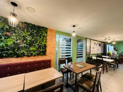 a restaurant with tables and chairs and a green wall at Xpeed Holiday Hotel in Kuala Lumpur