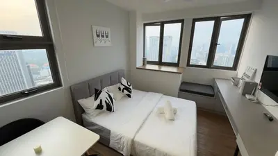 a room with a bed and a desk with windows at Nest Heaven Host in Kuala Lumpur