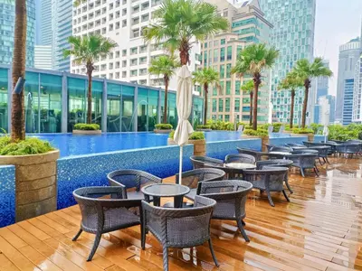 a hotel patio with tables and chairs and palm trees at Vortex Premium Apartment klcc in Kuala Lumpur