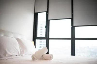 a white bed with a teddy bear sitting on it at Bangsar LRT Suites EST by LSA in Kuala Lumpur