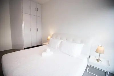 a bedroom with a white bed and a nightstand at Bangsar LRT Suites EST by LSA in Kuala Lumpur