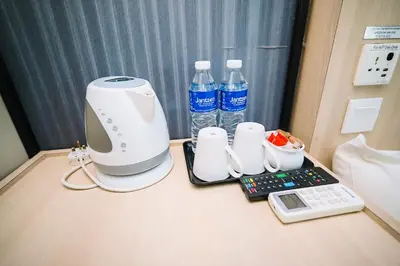 a hair dryer and cups and water bottles on a table at Swing & Pillows - TAR UMT Setapak in Kuala Lumpur