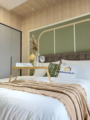 a bed with a wooden headboard with a table on it at ISYAK Homestay Cheras M Vertika KL in Kuala Lumpur