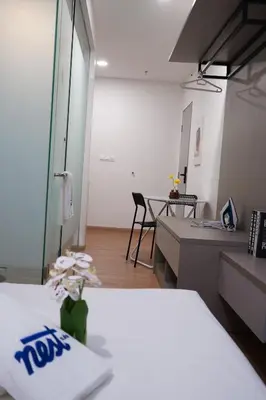 a room with two beds and a desk and a table at Riveria City KL Sentral by Nest Suite in Kuala Lumpur