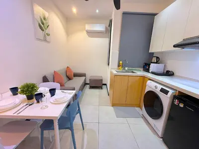 a kitchen and living room with a table and a washing machine at Neu Suites by Cozy Homes Near Gleneagles, KLCC & LRT in Kuala Lumpur