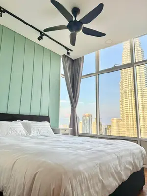 a bedroom with a bed with a ceiling fan and large windows at Sky Suites Klcc By Stayner in Kuala Lumpur