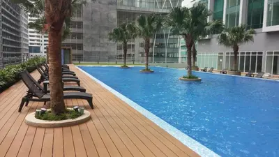 a large swimming pool with palm trees in a building at Soho Suites Pavilion by LSA in Kuala Lumpur