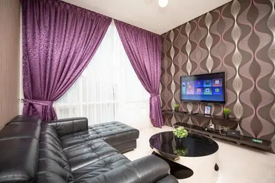 a living room with a leather couch and a tv at Soho Suites Pavilion by LSA in Kuala Lumpur