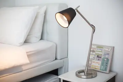 a lamp on a table next to a bed at Soho Suites Pavilion by LSA in Kuala Lumpur