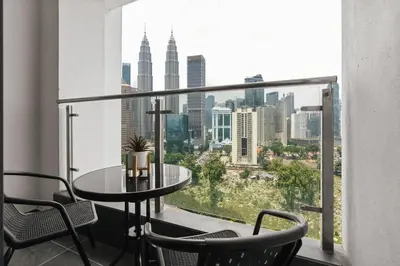 a balcony with a table and chairs and a view of the city at Legasi 3 Premium Bedroom With KLCC View 10min Walk to KLCC Comes With Board Games and PS4 Fit Up To 10PAX in Kuala Lumpur