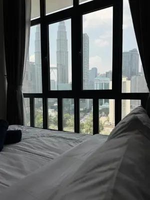 a bed in front of a window with a city view at Legasi 3 Premium Bedroom With KLCC View 10min Walk to KLCC Comes With Board Games and PS4 Fit Up To 10PAX in Kuala Lumpur