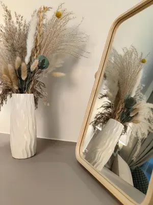 a white vase with feathers in it next to a mirror at TRX Agile Bukit Bintang 2 Bedroom Deluxe Suites in Kuala Lumpur